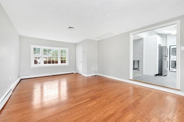 unfurnished living room featuring a baseboard heating unit, light wood-style floors, and baseboards
