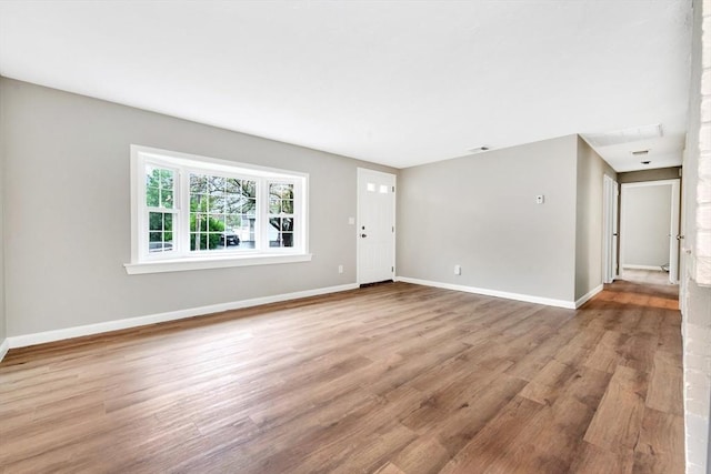 unfurnished living room with wood finished floors and baseboards