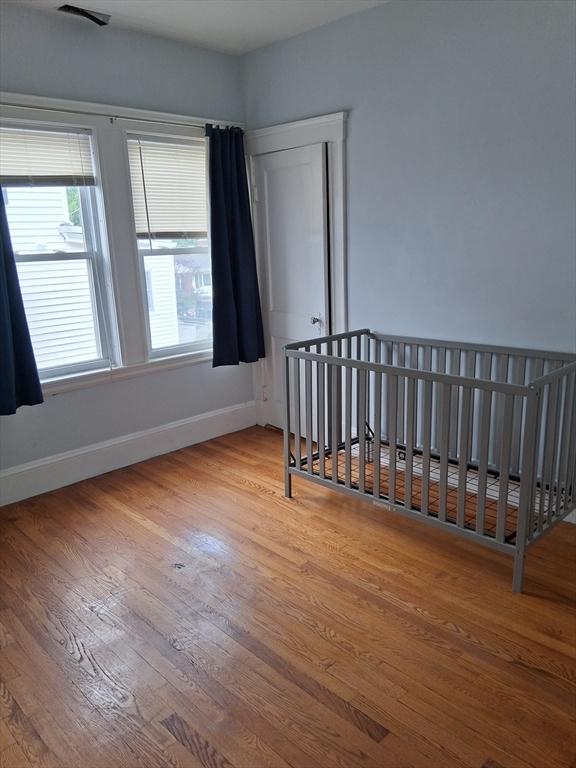 513 Washington Ave, Chelsea, MA 02150 - unfurnished bedroom featuring wood finished floors, baseboards, and a crib