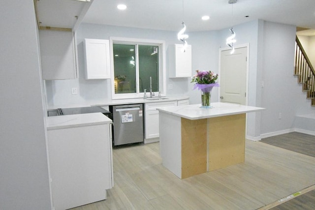 kitchen with white cabinetry, a center island, hanging light fixtures, light wood-type flooring, and stainless steel dishwasher