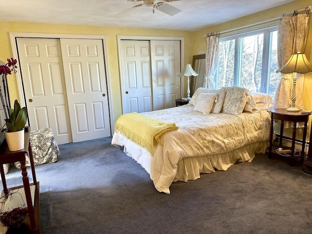 bedroom featuring ceiling fan, two closets, and dark colored carpet