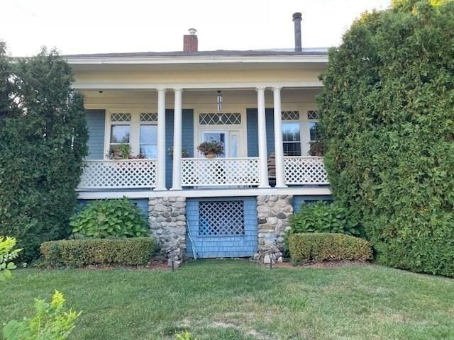 back of house featuring a porch and a lawn