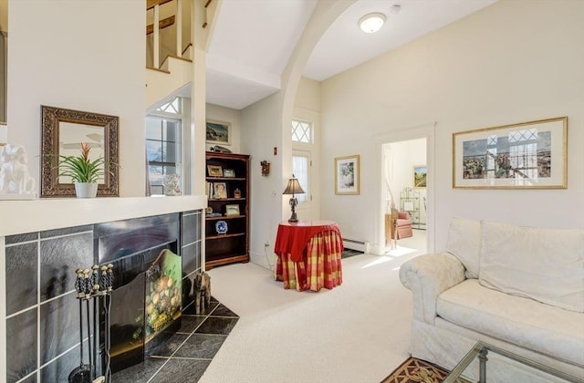 living room featuring a towering ceiling, a baseboard radiator, and dark carpet