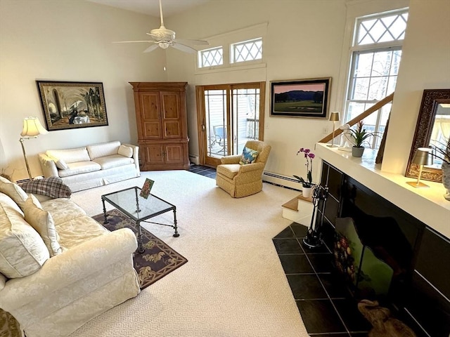 living room featuring ceiling fan, a towering ceiling, a baseboard radiator, and dark colored carpet