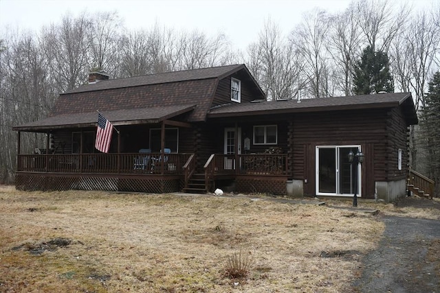 rear view of property featuring log exterior, a shingled roof, and a gambrel roof