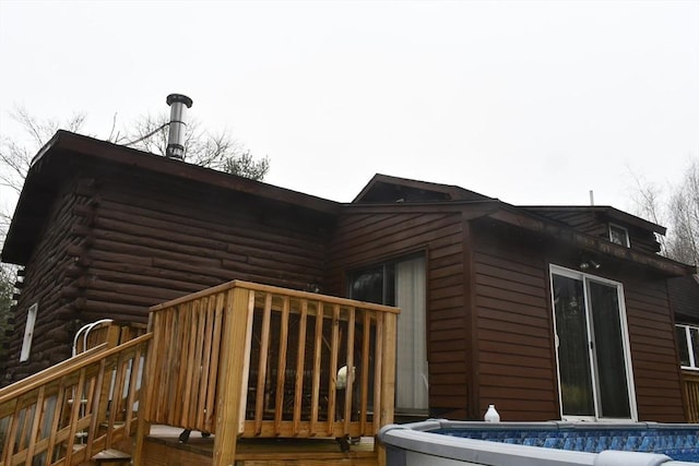 view of home's exterior with a deck, a swimming pool, and log siding