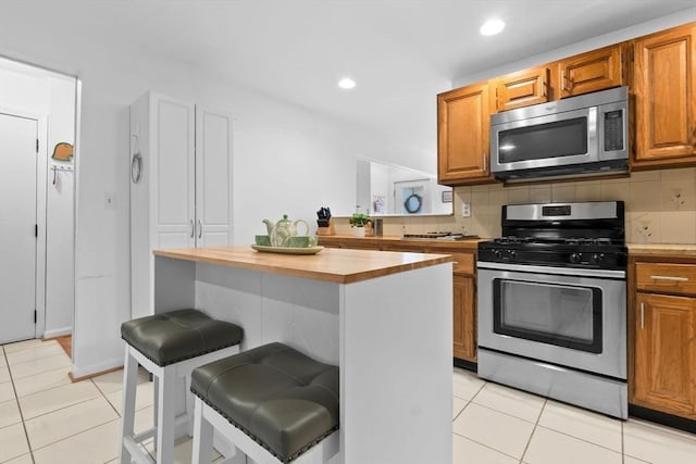 29 1st St Unit C, Salem, MA 01970 - kitchen featuring appliances with stainless steel finishes, a breakfast bar area, light tile patterned floors, backsplash, and recessed lighting