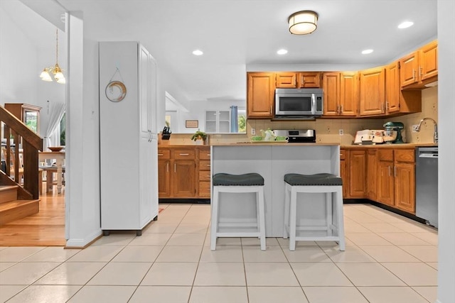 29 1st St Unit C, Salem, MA 01970 - kitchen with stainless steel appliances, a breakfast bar, recessed lighting, light countertops, and light tile patterned floors