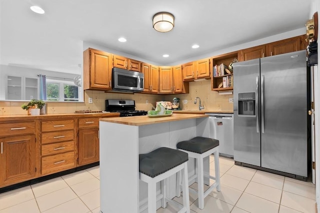 29 1st St Unit C, Salem, MA 01970 - kitchen with appliances with stainless steel finishes, light tile patterned flooring, recessed lighting, a kitchen breakfast bar, and tasteful backsplash
