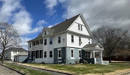 view of side of property featuring a garage, a yard, a porch, and a balcony