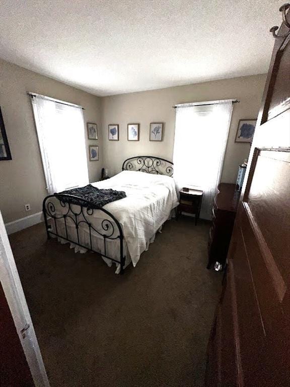 bedroom with dark colored carpet and a textured ceiling
