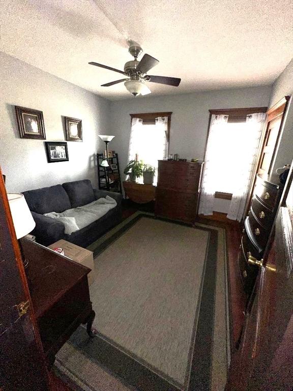 living room featuring a textured ceiling, carpet flooring, and ceiling fan