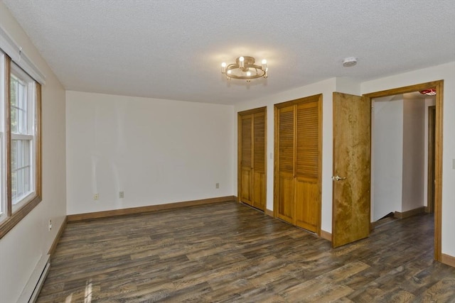 8 Field St, Southwick, MA 01077 - unfurnished bedroom featuring baseboard heating, two closets, dark wood-type flooring, a textured ceiling, and baseboards