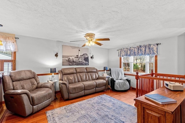 living area featuring a textured ceiling, ceiling fan, and light wood finished floors