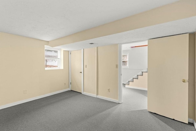 basement featuring stairs, carpet floors, a wealth of natural light, and baseboards