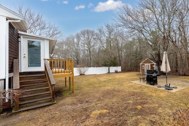 view of yard featuring an outbuilding, a patio, a storage unit, a deck, and a fenced backyard