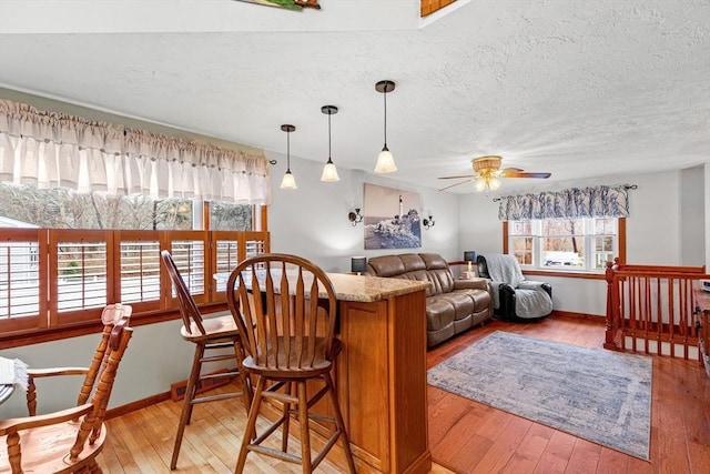 living area featuring light wood-style floors, a textured ceiling, and baseboards