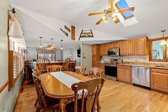 dining room with light wood-style flooring, vaulted ceiling, and a ceiling fan