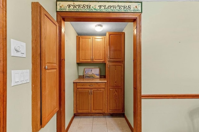 hall featuring light tile patterned floors and baseboards