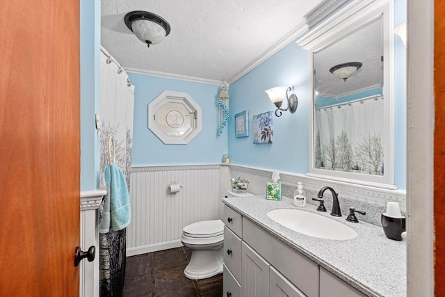 full bathroom with wainscoting, toilet, ornamental molding, a textured ceiling, and vanity