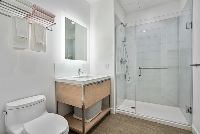 bathroom featuring a shower with door, vanity, and toilet