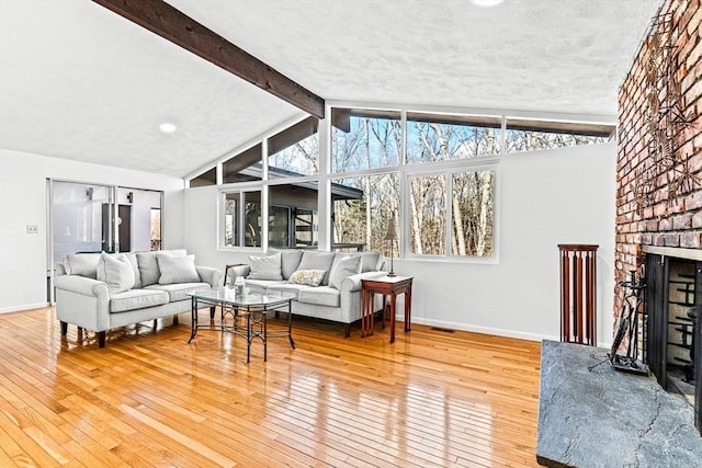 living room featuring vaulted ceiling with beams, wood-type flooring, and a healthy amount of sunlight