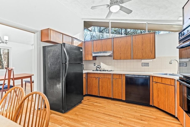 kitchen with lofted ceiling, sink, backsplash, black appliances, and light wood-type flooring