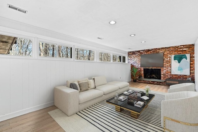 living room with a brick fireplace and light wood-type flooring