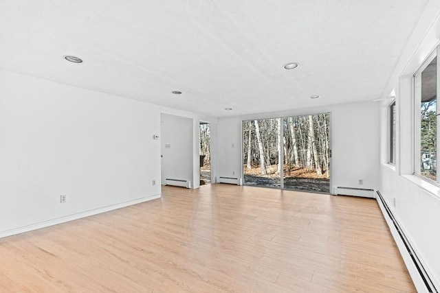 empty room with light hardwood / wood-style floors and a baseboard heating unit