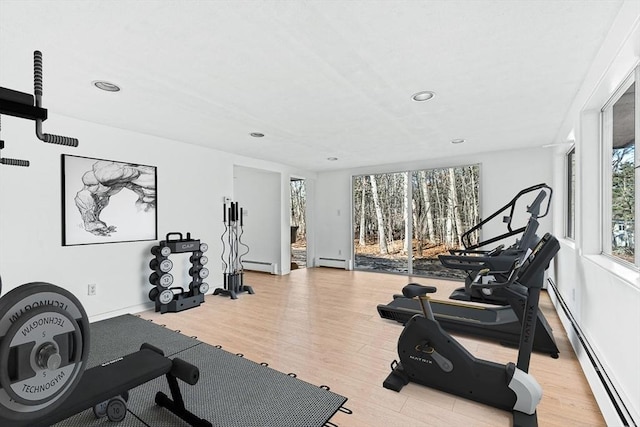 exercise area featuring baseboard heating and light hardwood / wood-style flooring