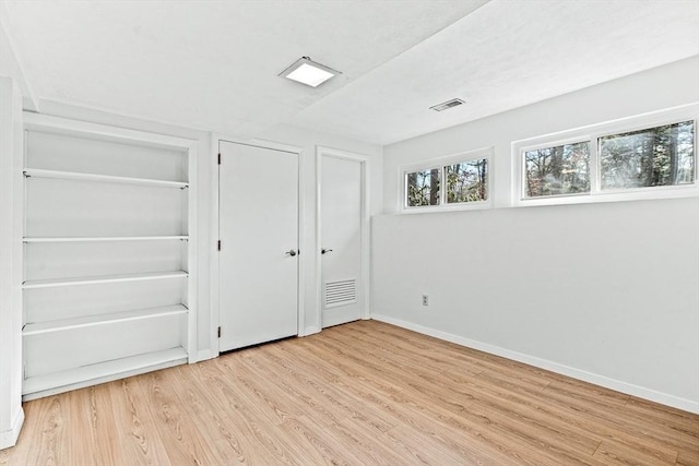 unfurnished bedroom with light hardwood / wood-style floors and two closets