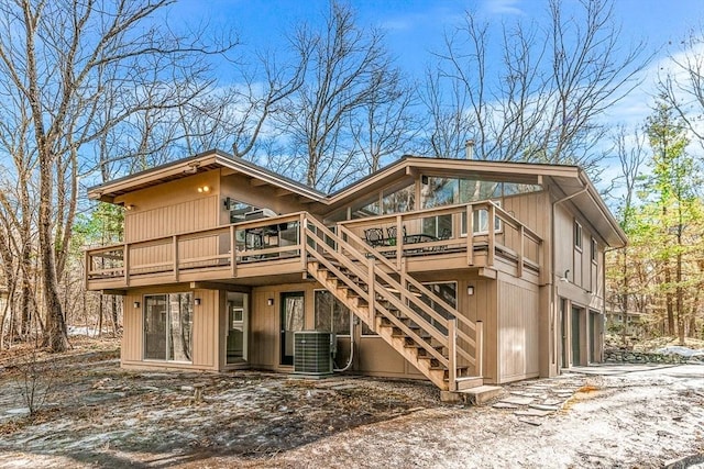 snow covered house with a garage, central AC unit, and a deck