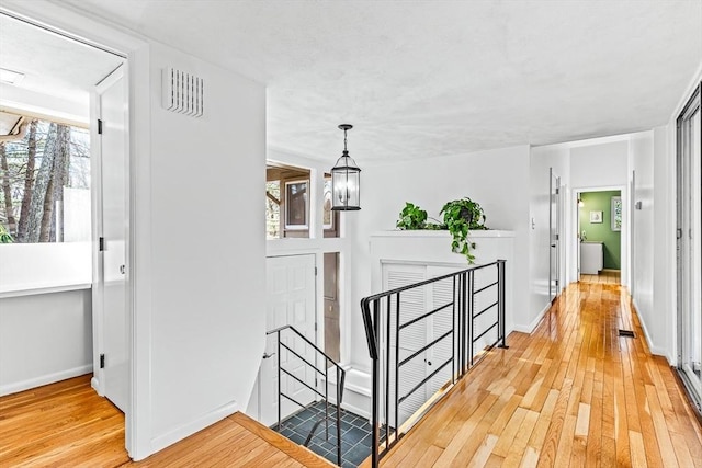 corridor featuring light hardwood / wood-style flooring and a notable chandelier