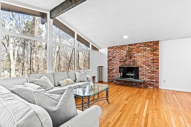 living room featuring high vaulted ceiling, a brick fireplace, hardwood / wood-style floors, and beam ceiling