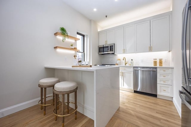 kitchen featuring light countertops, light wood-type flooring, a kitchen bar, and stainless steel appliances