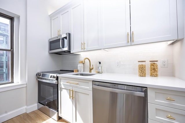kitchen with light countertops, appliances with stainless steel finishes, decorative backsplash, and a sink