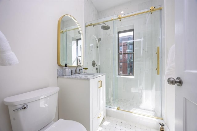bathroom with toilet, a marble finish shower, and vanity