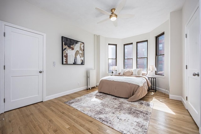 bedroom featuring baseboards, a ceiling fan, radiator, and light wood-style floors