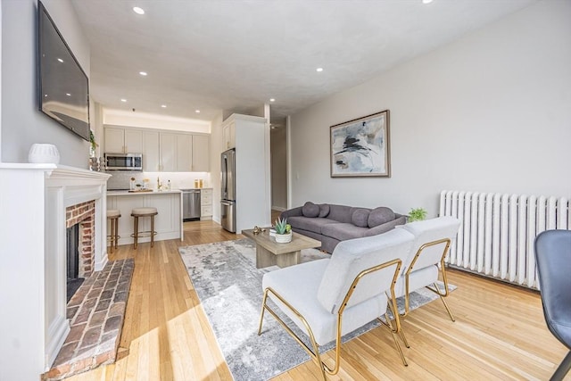 living area featuring radiator heating unit, recessed lighting, light wood-style floors, and a fireplace