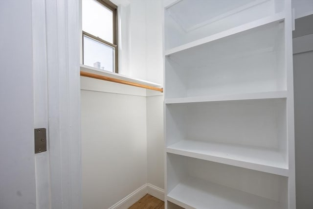 walk in closet with wood finished floors