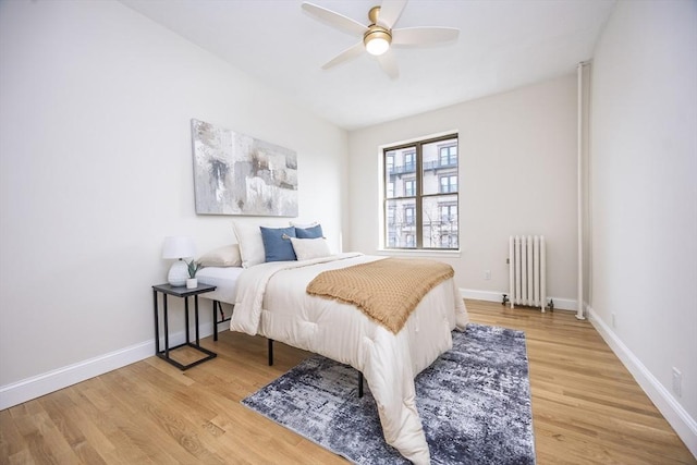bedroom featuring wood finished floors, radiator heating unit, and baseboards