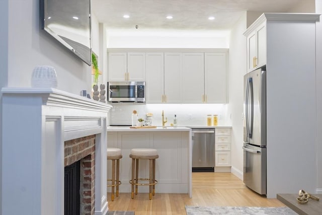 kitchen with white cabinets, light countertops, a kitchen breakfast bar, stainless steel appliances, and backsplash