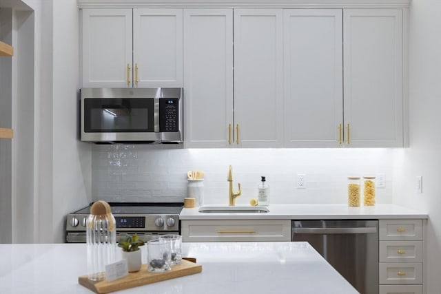 kitchen with light countertops, a sink, backsplash, and appliances with stainless steel finishes