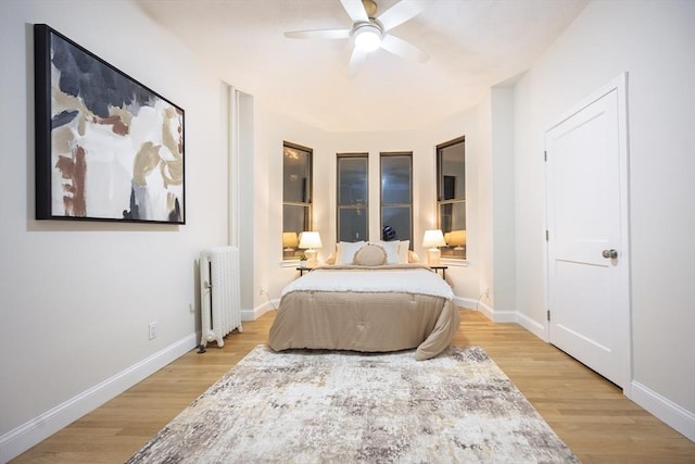 bedroom featuring radiator, light wood finished floors, and baseboards