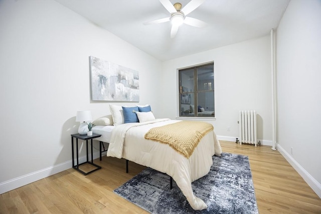 bedroom featuring baseboards, radiator, and wood finished floors