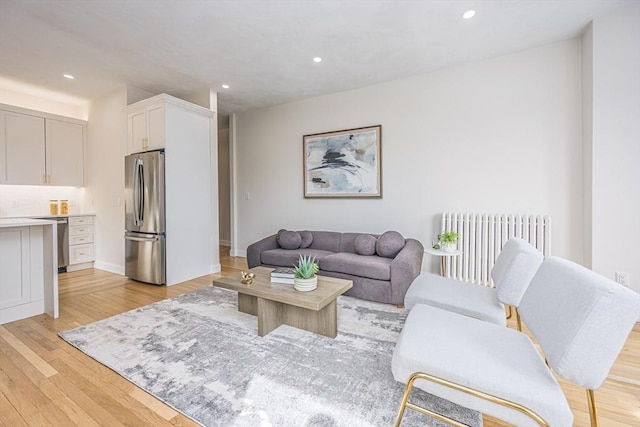 living area with light wood finished floors, radiator heating unit, and recessed lighting