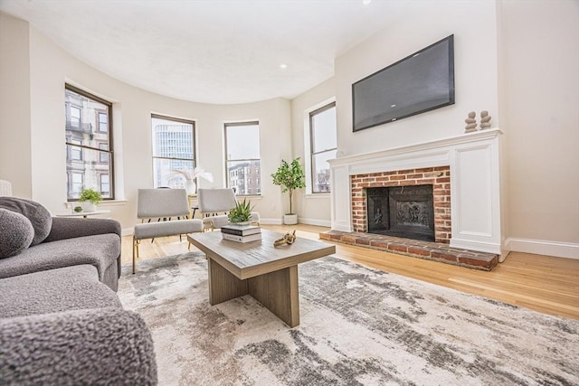 living area featuring a fireplace, baseboards, and wood finished floors