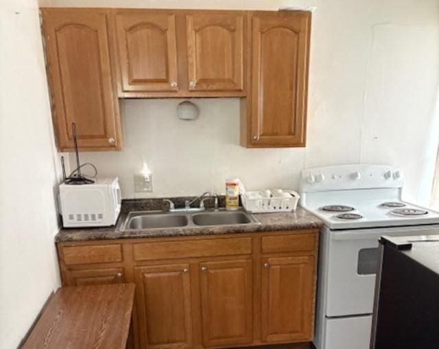 1098 Pleasant St, Palmer, MA 01069 - kitchen featuring white appliances, a sink, dark countertops, and brown cabinetry
