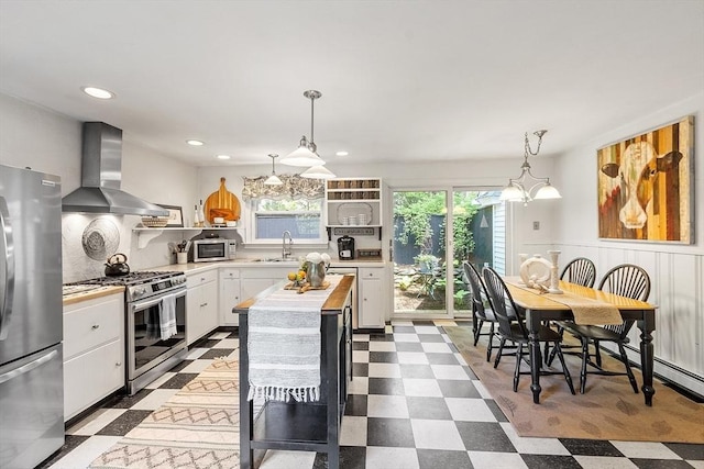 24 Summit Ave, Chelmsford, MA 01824 - kitchen featuring appliances with stainless steel finishes, wall chimney range hood, dark flooring, white cabinets, and hanging light fixtures