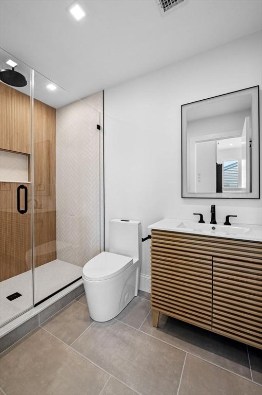 bathroom with toilet, a stall shower, tile patterned flooring, vanity, and recessed lighting